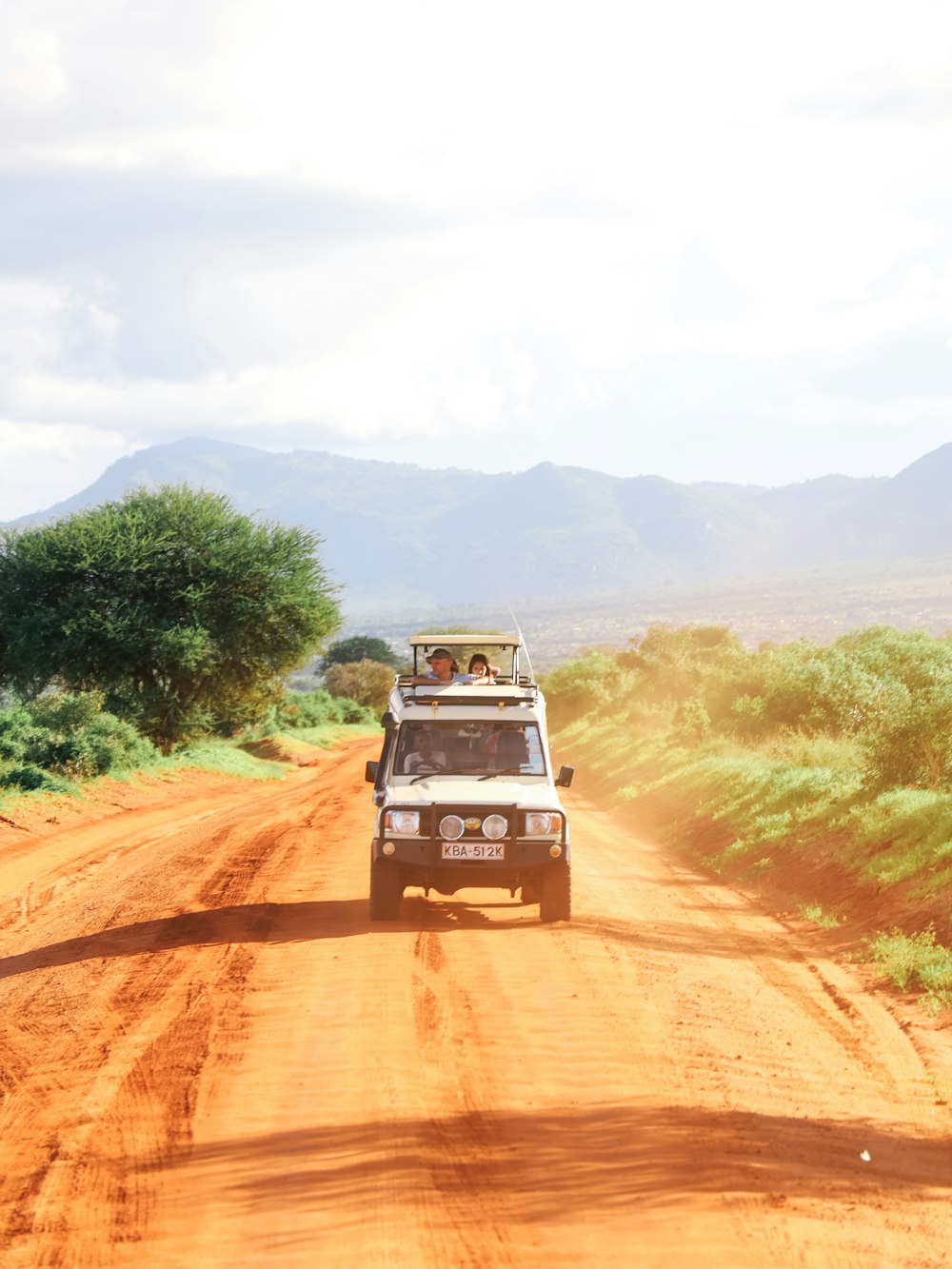 a safari vehicle driving down a dirt road