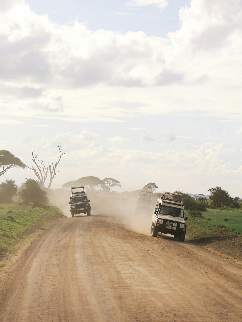 a couple of trucks driving down a dirt road