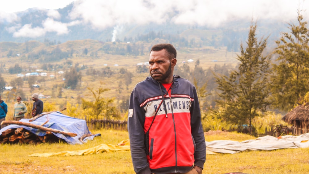 a man in a red and blue jacket standing in a field