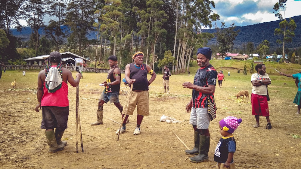 a group of people standing on top of a dirt field