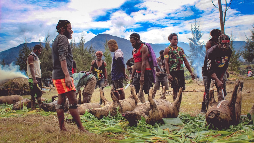 a group of men standing around dead sheep