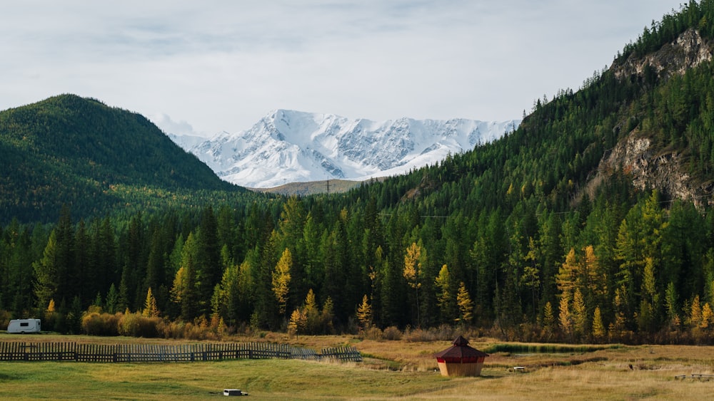 a field with a barn and mountains in the background