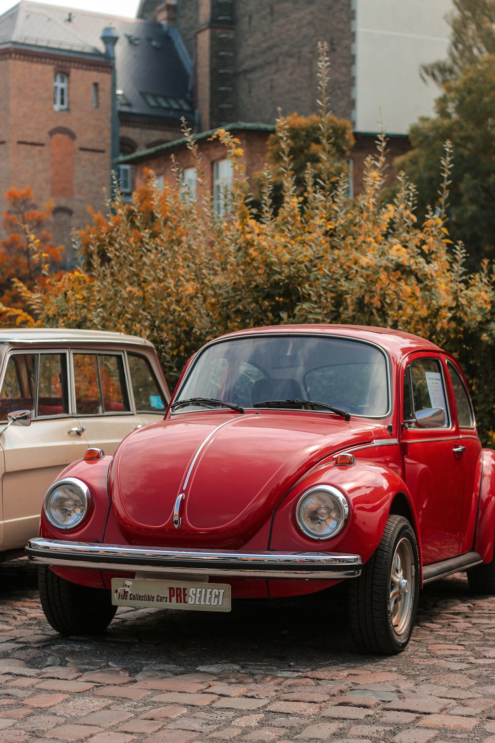 two old cars parked next to each other on a brick road