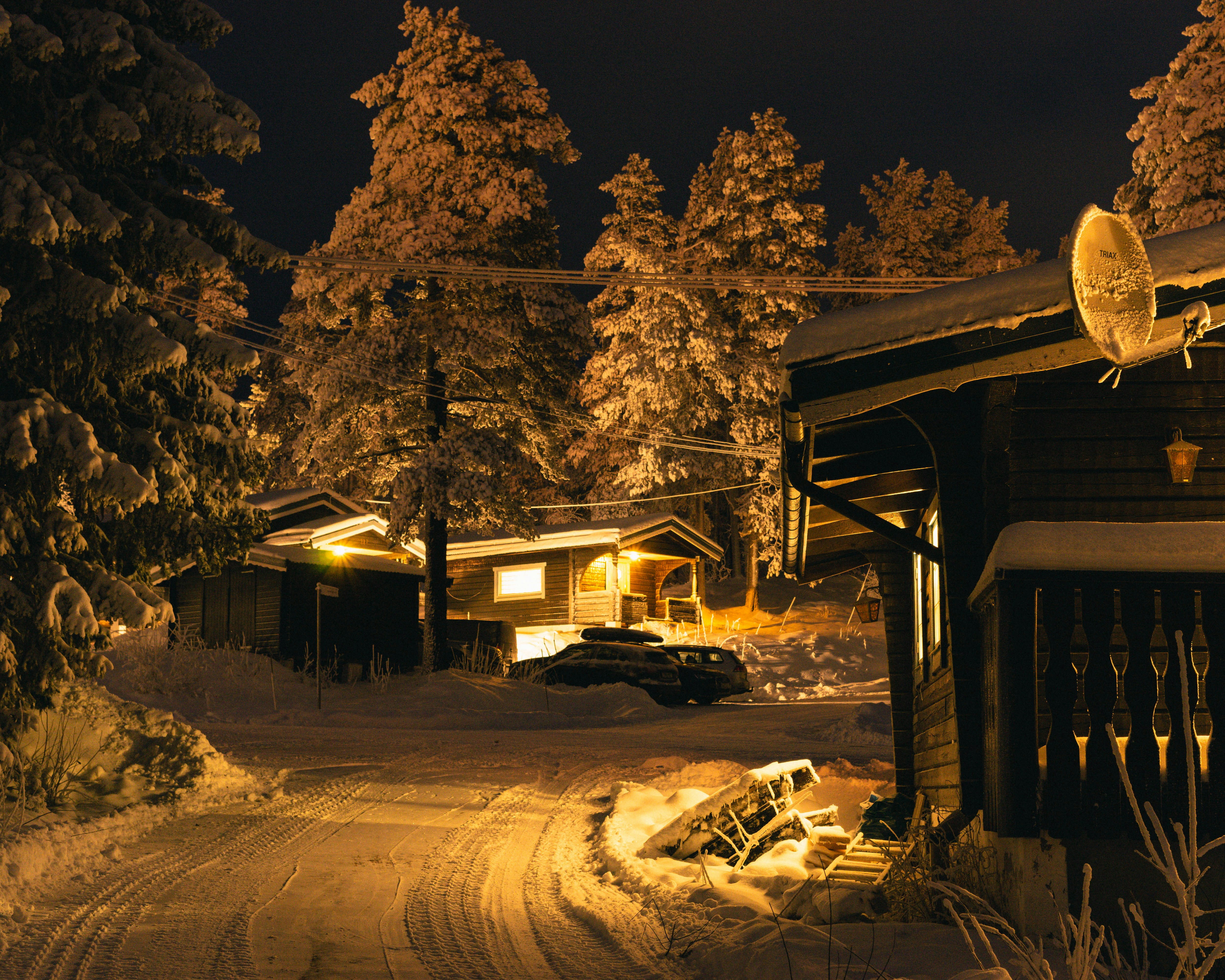a snowy road with a house and a car in the background
