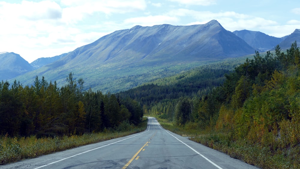 an empty road with mountains in the background