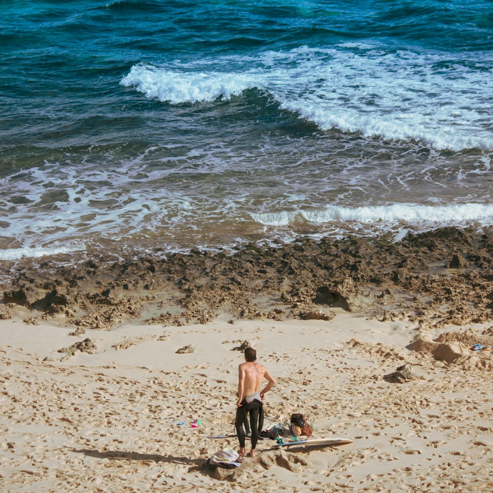 Un uomo in piedi sulla cima di una spiaggia sabbiosa vicino all'oceano