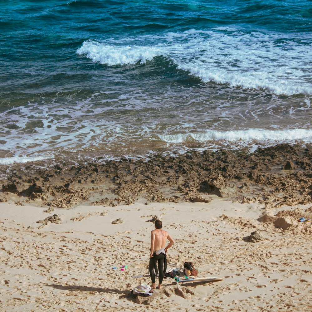 a man standing on top of a sandy beach next to the ocean