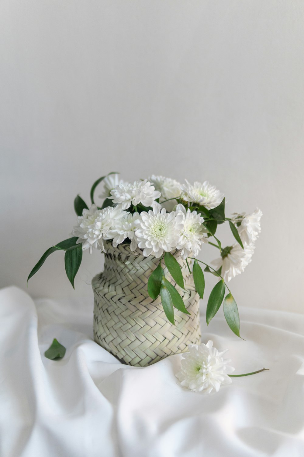 a basket of white flowers on a white cloth