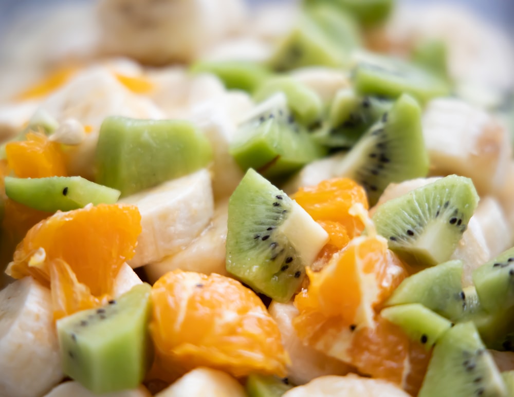 a close up of a fruit salad with kiwi, oranges, and bananas