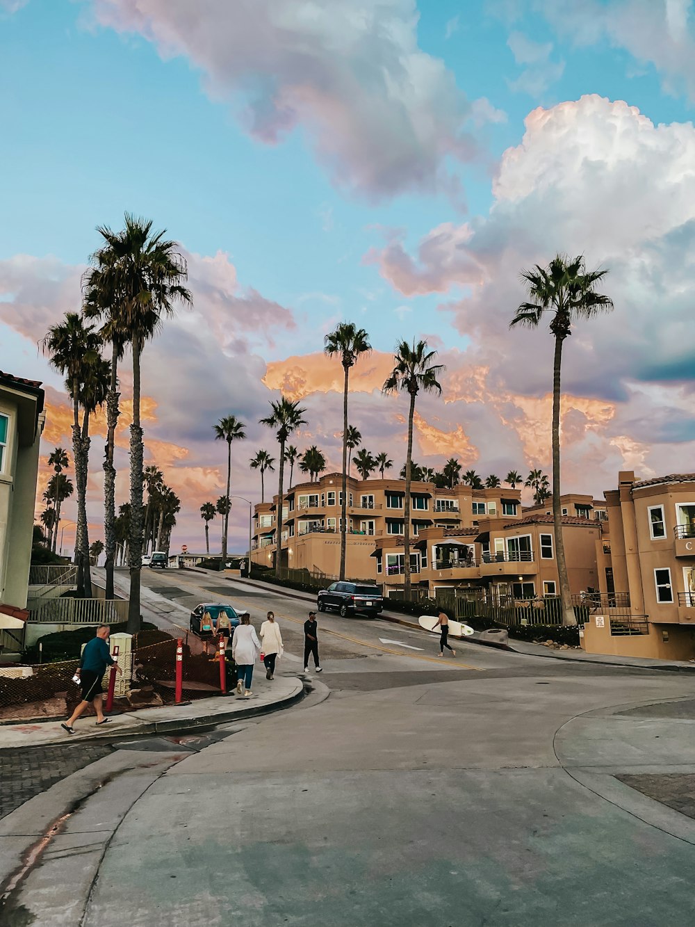 a group of people walking down a street next to palm trees