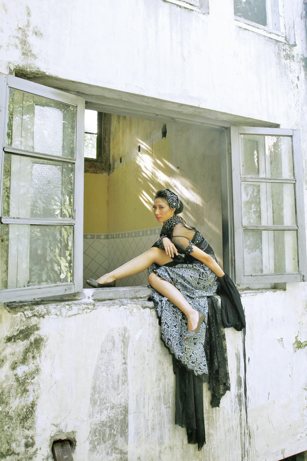 a woman sitting on a window sill next to a building