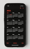 A smartphone displaying a calendar for the year 2022. The months are arranged in three rows on a black screen with white numbers and red accents for the year and certain days.