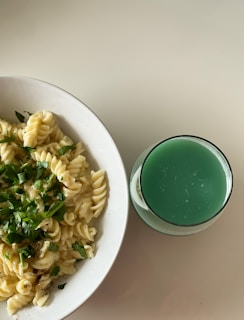 A vibrant bowl of creamy avocado pasta garnished with fresh herbs and a sprinkle of chili flakes.