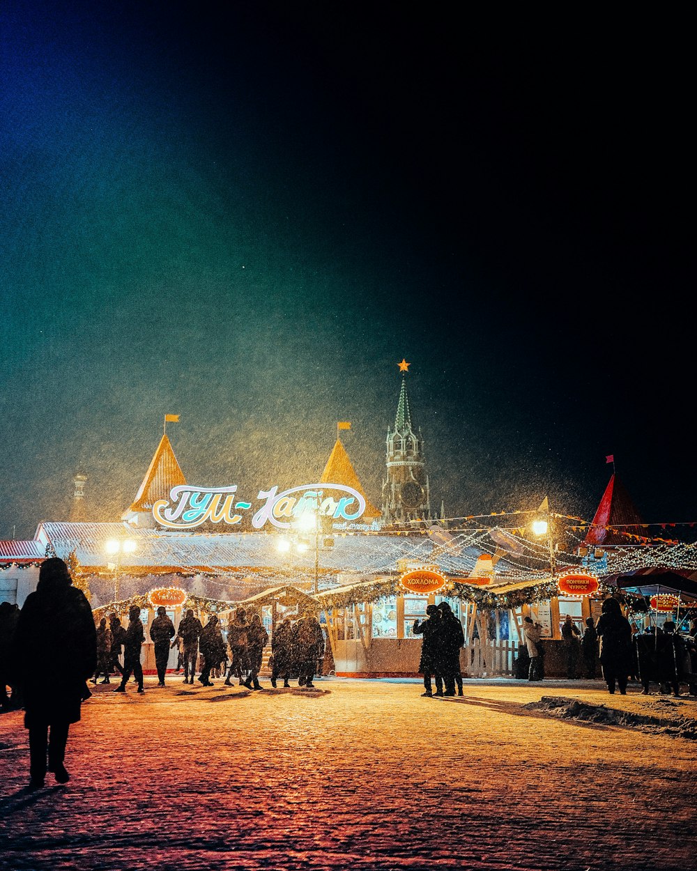 a crowd of people walking around a carnival at night