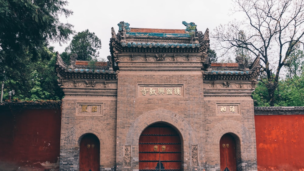 a tall gate with a red door in front of a red wall