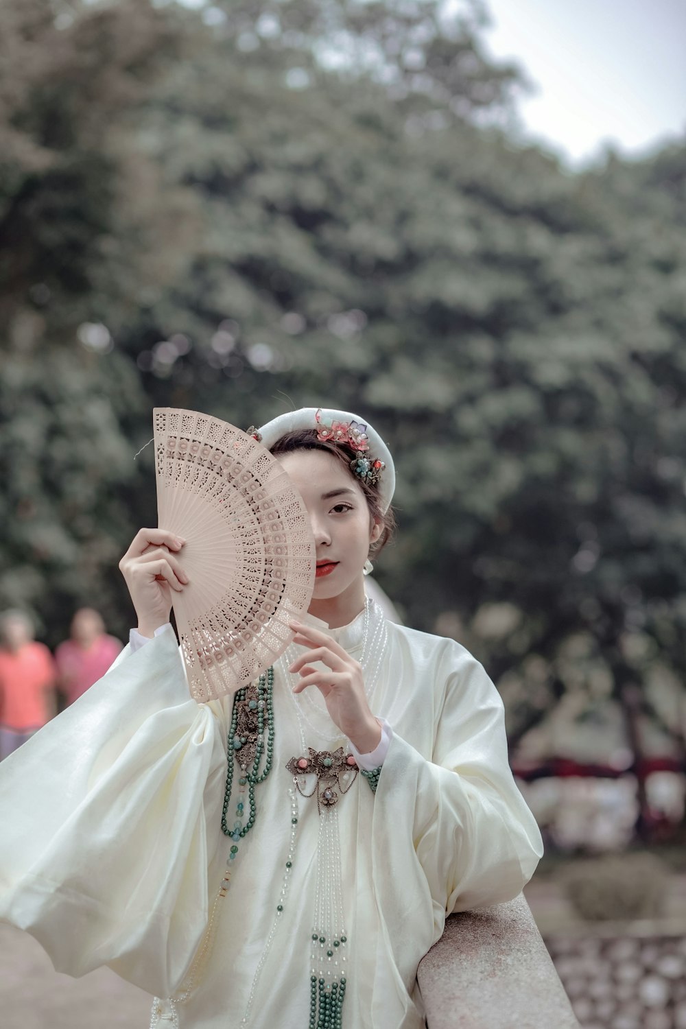 a woman in a white dress holding a fan