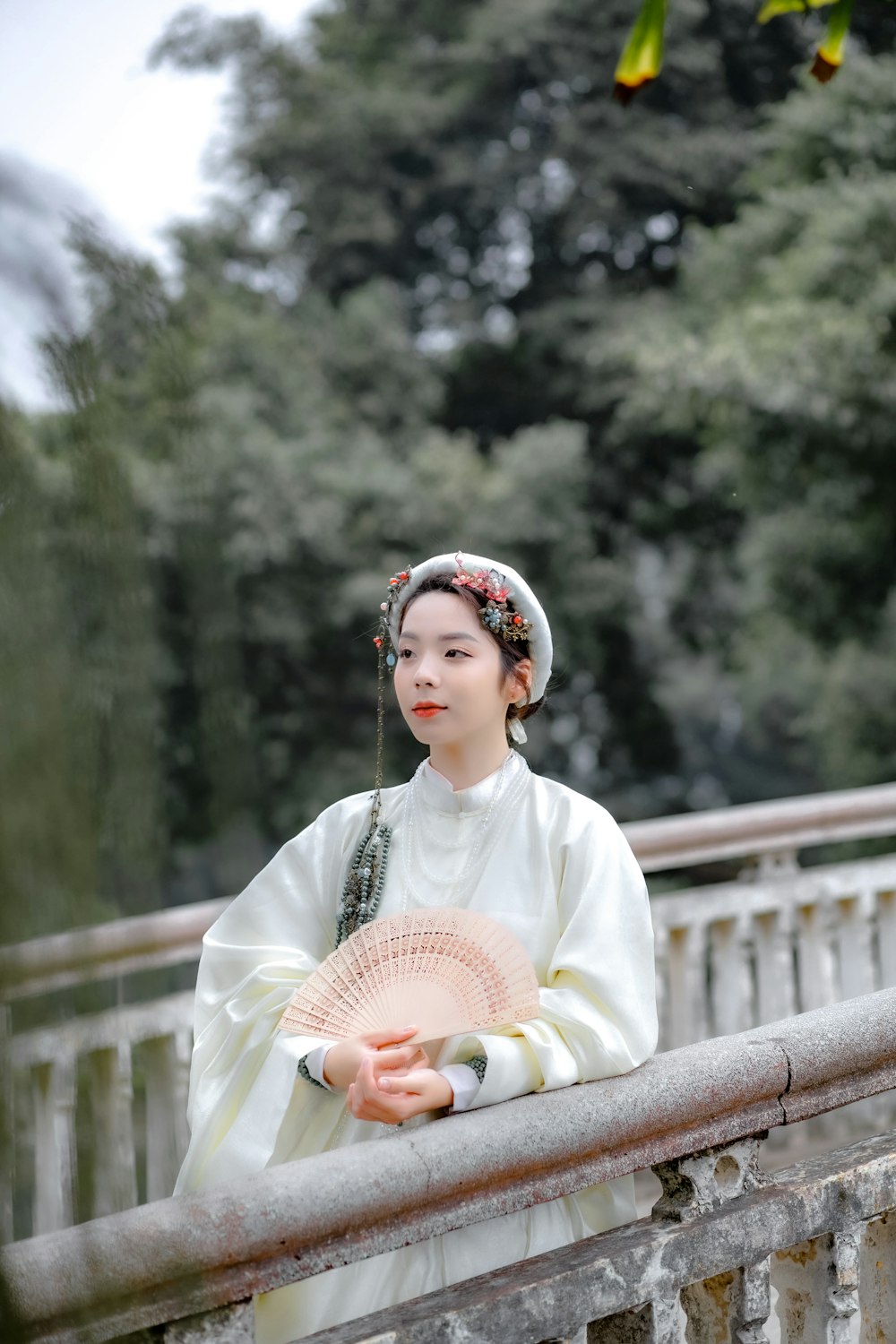 a woman in a white dress holding a pink fan