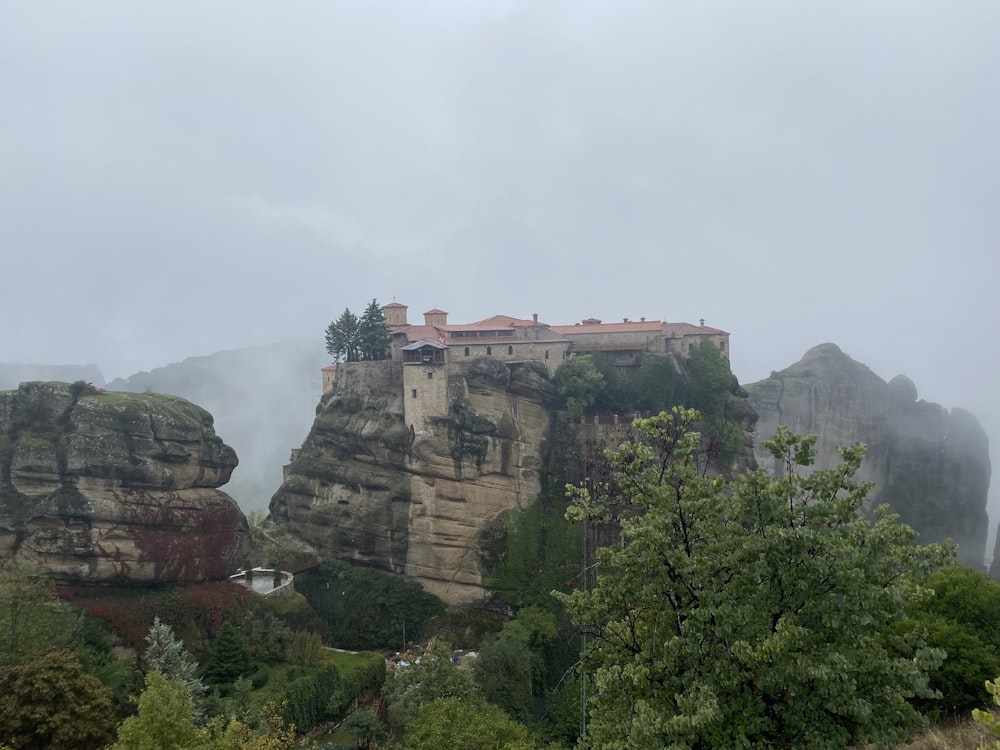 a castle perched on top of a cliff surrounded by trees