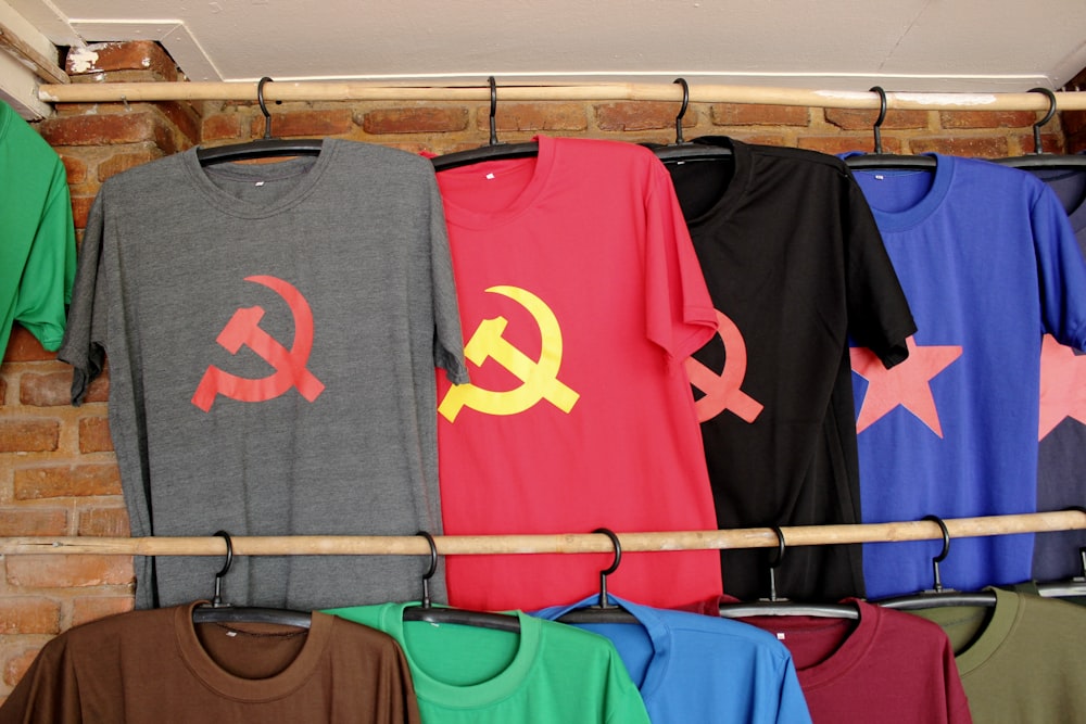 Un estante de camisetas colgadas en una pared de ladrillo