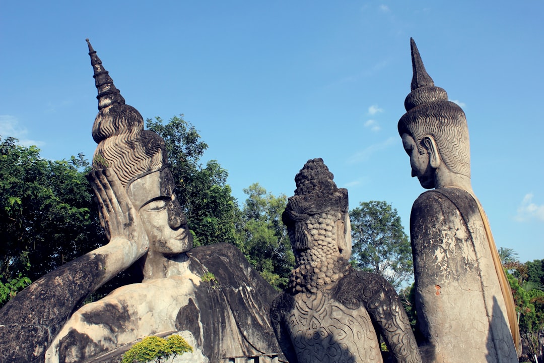 a group of statues sitting next to each other, Leaning statues at the Buddha Park in Laos. A peaceful place nestled in a