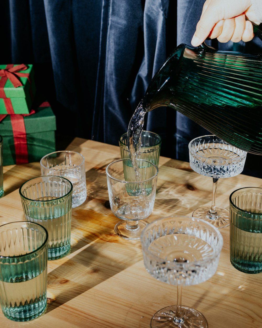 a person pouring water into glasses on a table