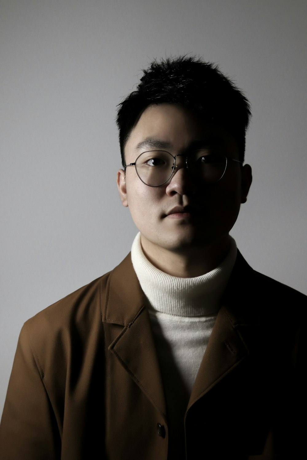 a man wearing glasses and a brown jacket