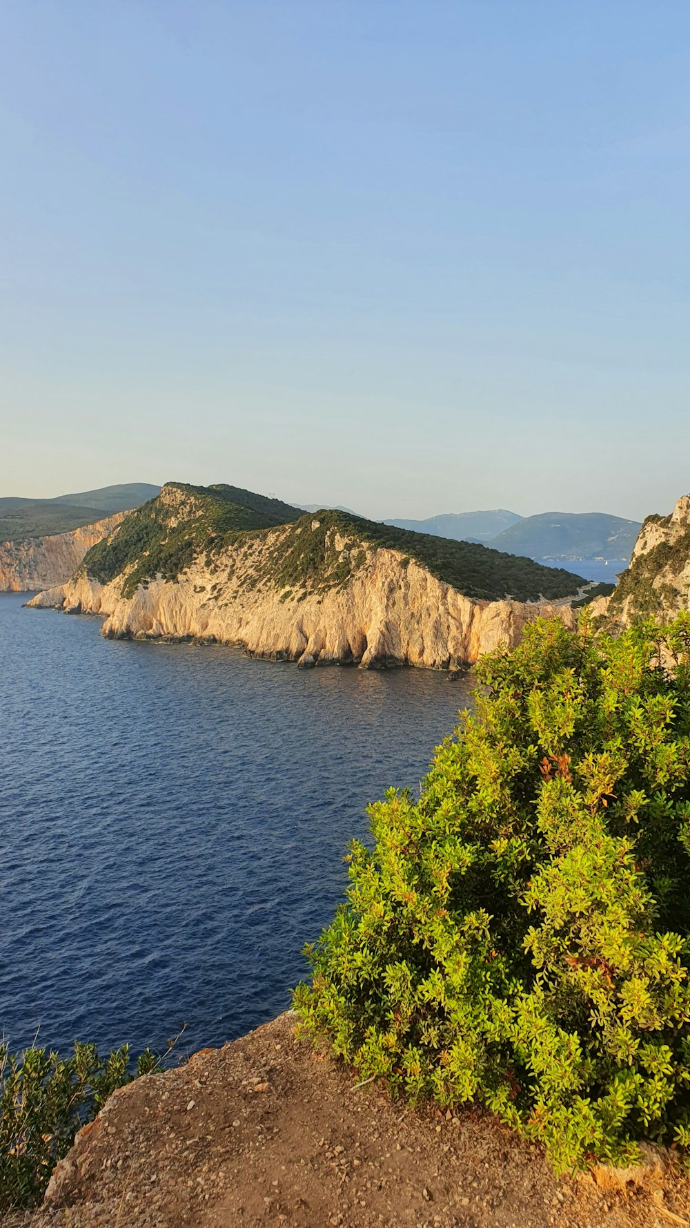 a large body of water sitting next to a lush green hillside