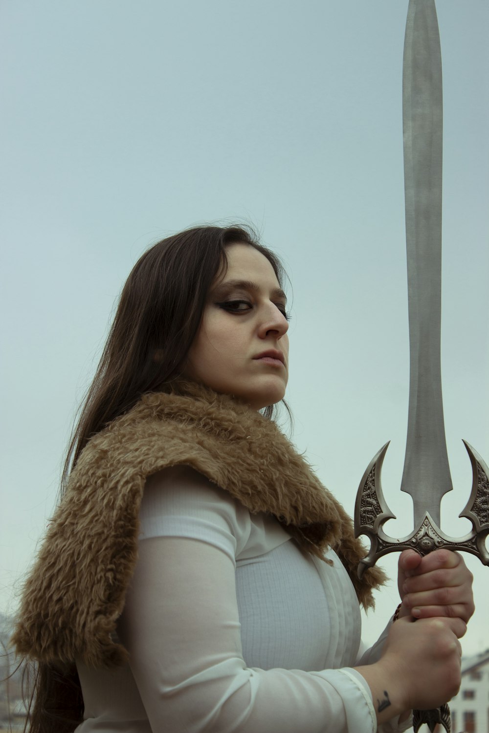 a woman in a fur vest holding a large sword