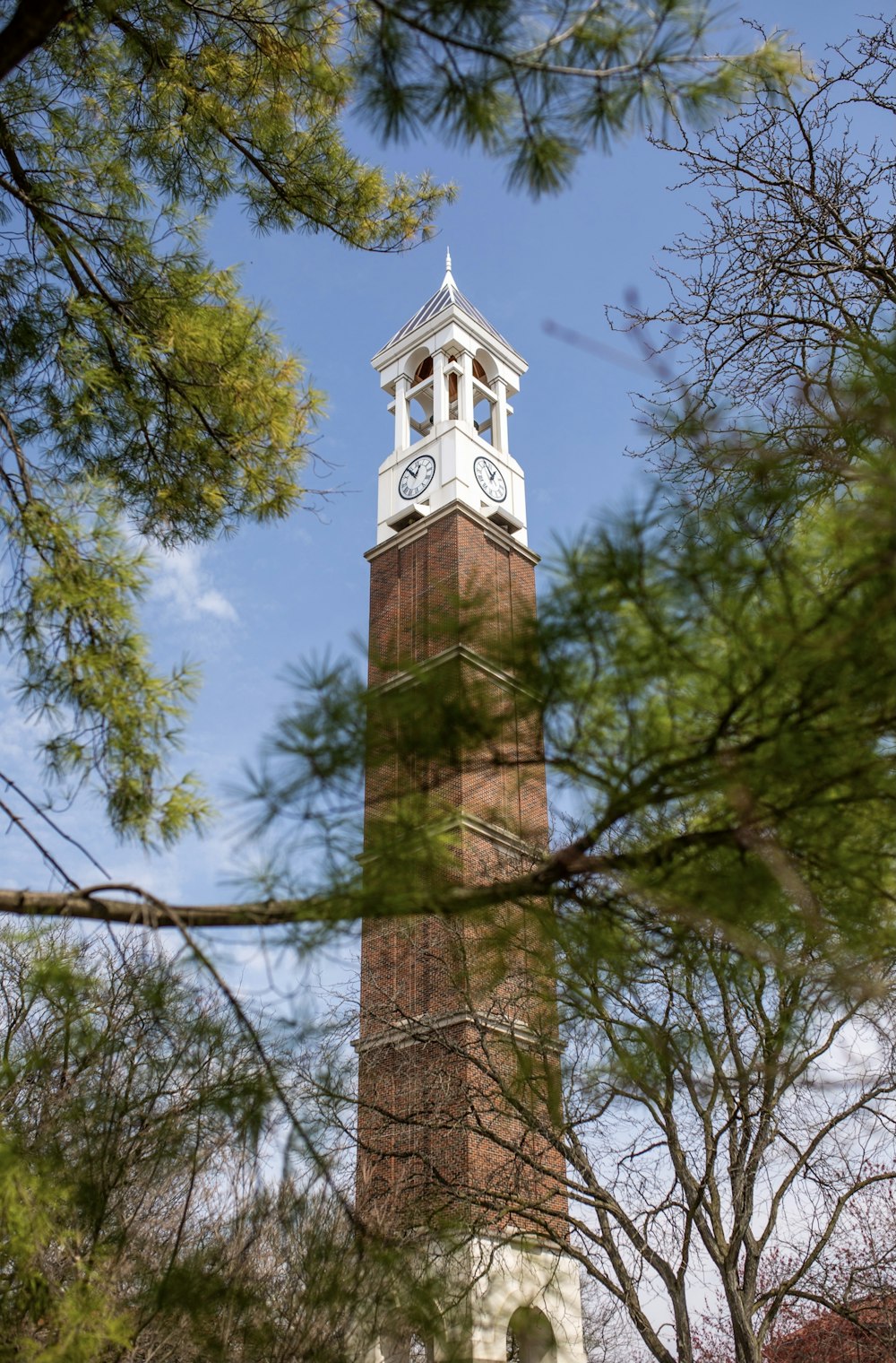 uma grande torre alta com um relógio ao lado de uma árvore