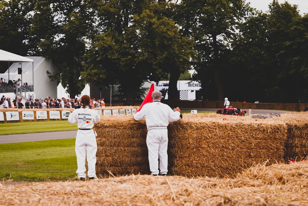 a couple of men standing next to a pile of hay