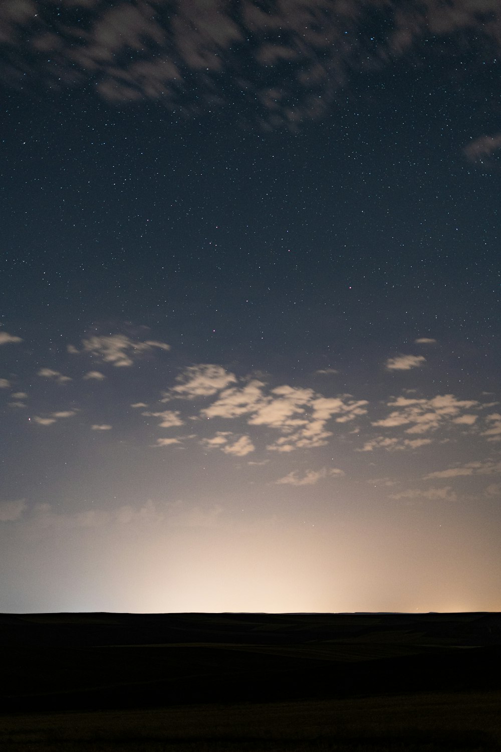 the night sky with a few clouds and stars