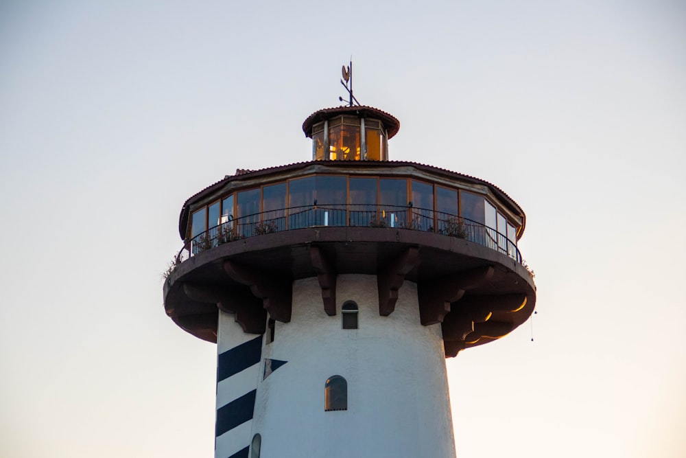 a white and black lighthouse with a sky background