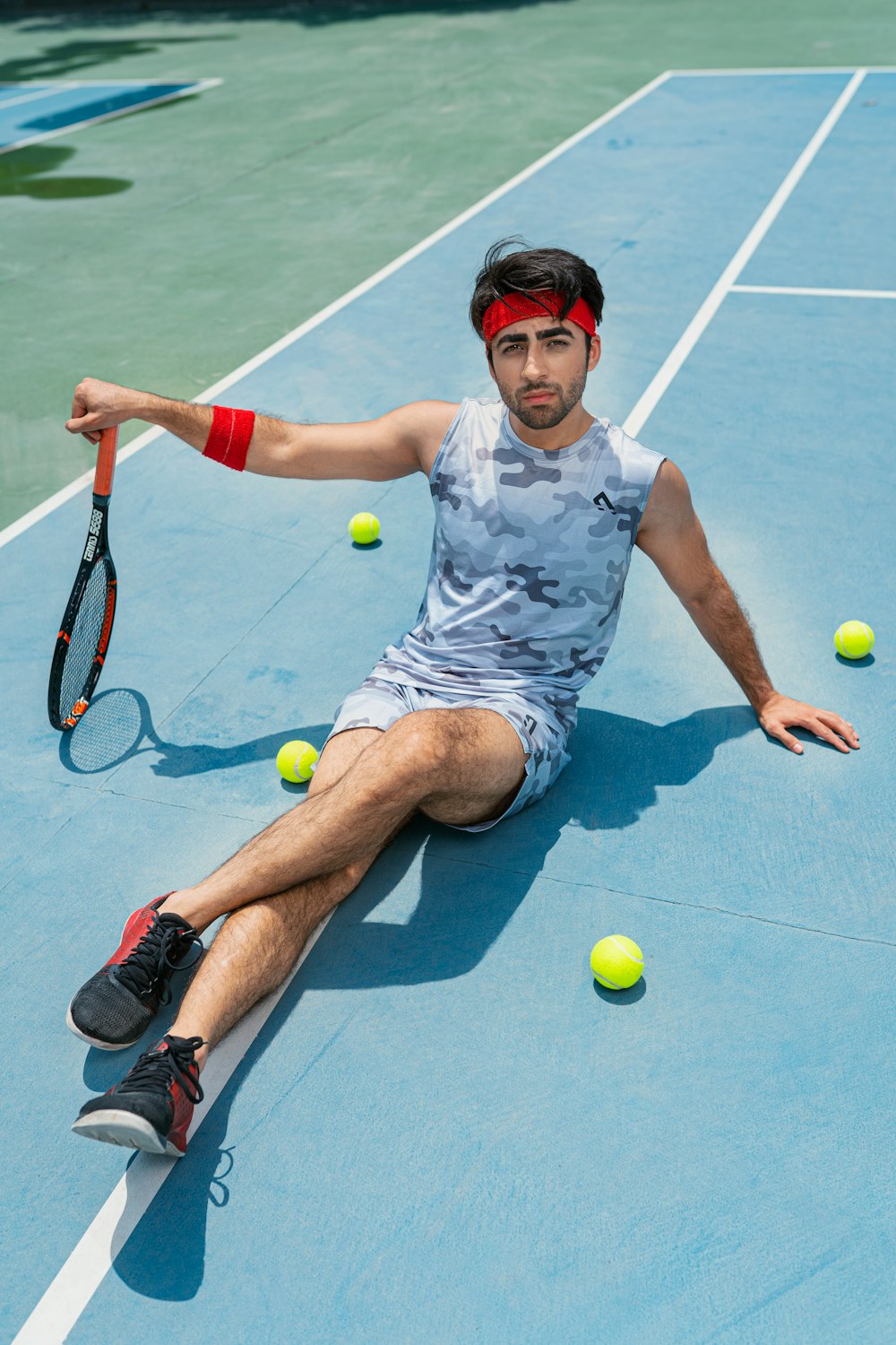 a man sitting on a tennis court holding a tennis racquet