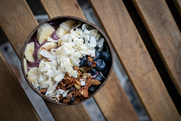 A vibrant açai bowl topped with fresh tropical fruits and granola, served on a rustic wooden table.