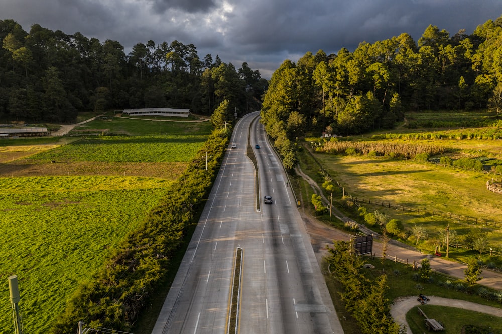 a long empty road in the middle of a lush green field