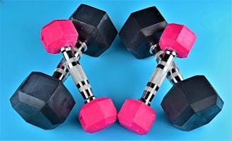 a pair of pink and black dumbs on a blue background