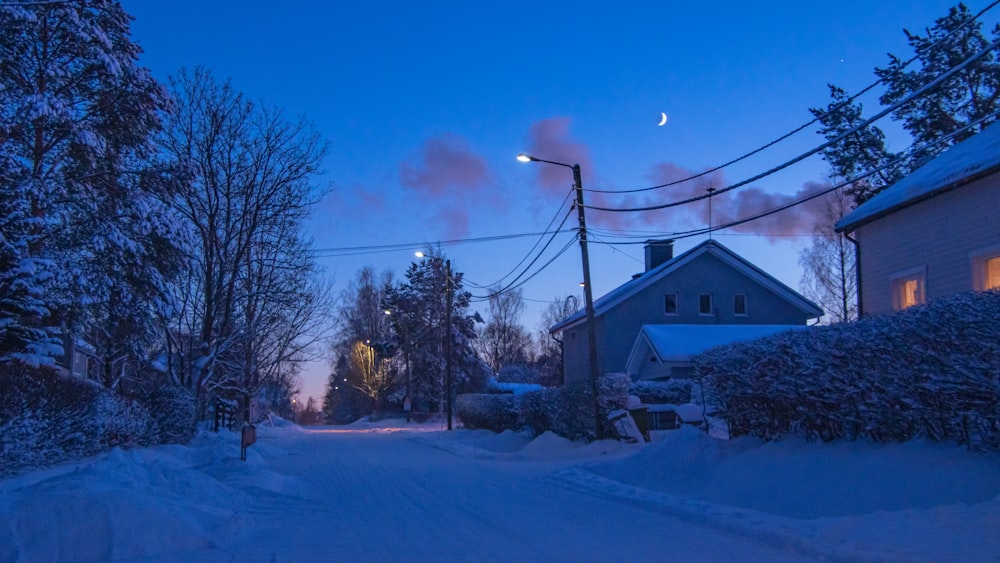 a snowy street with a house in the background