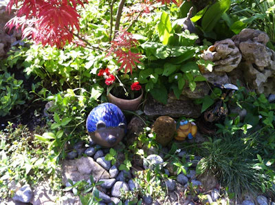 A vibrant garden scene featuring colorful garden ornaments nestled among lush greenery.