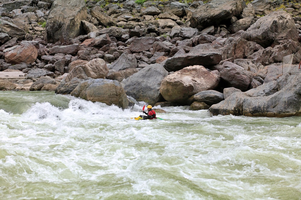 a person in a kayak on a river surrounded by rocks