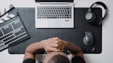 a person sitting at a desk with a laptop and headphones