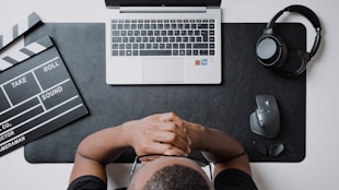 a person sitting at a desk with a laptop and headphones