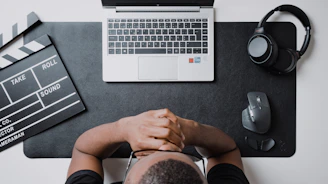 A dark, minimalistic cinematic-themed workspace with a laptop, film reels, and a microphone.