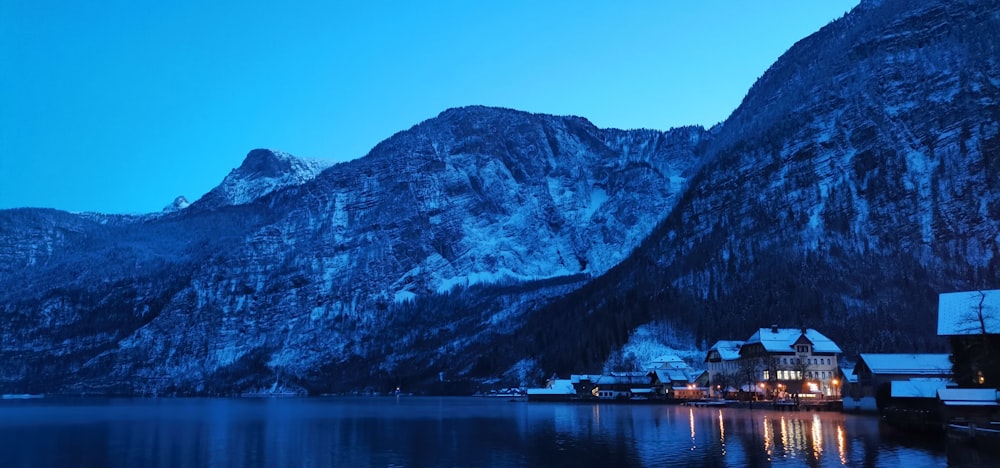 a lake surrounded by snow covered mountains at night