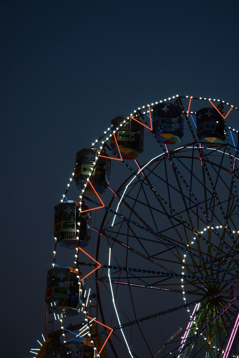 a ferris wheel lit up at night with a sky background