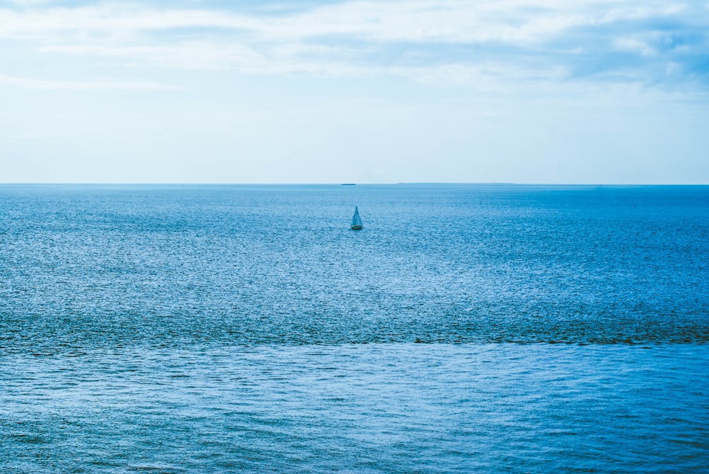 a lone sailboat in the middle of the ocean