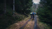 A group of friends riding Ubco bikes through a forest trail.
