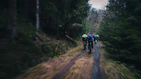 A group of friends riding Ubco bikes through a forest trail.