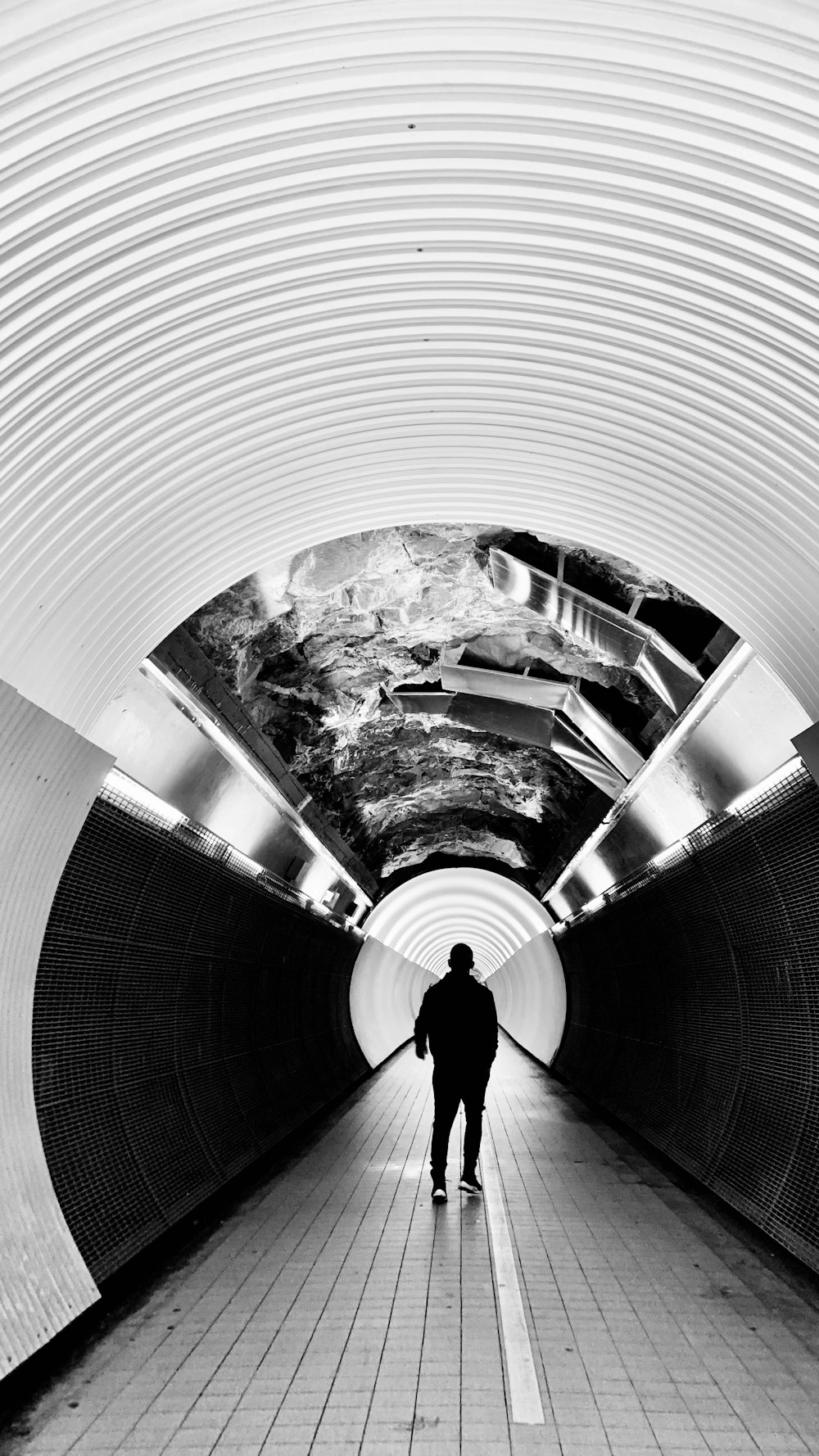 a man is walking down a long tunnel