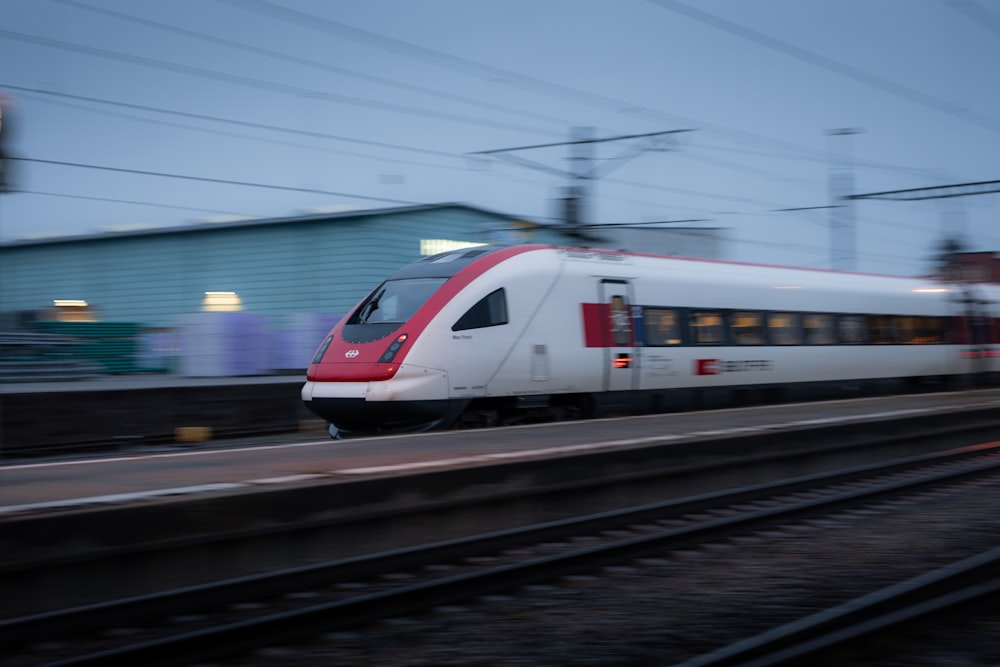 a red and white train traveling down train tracks