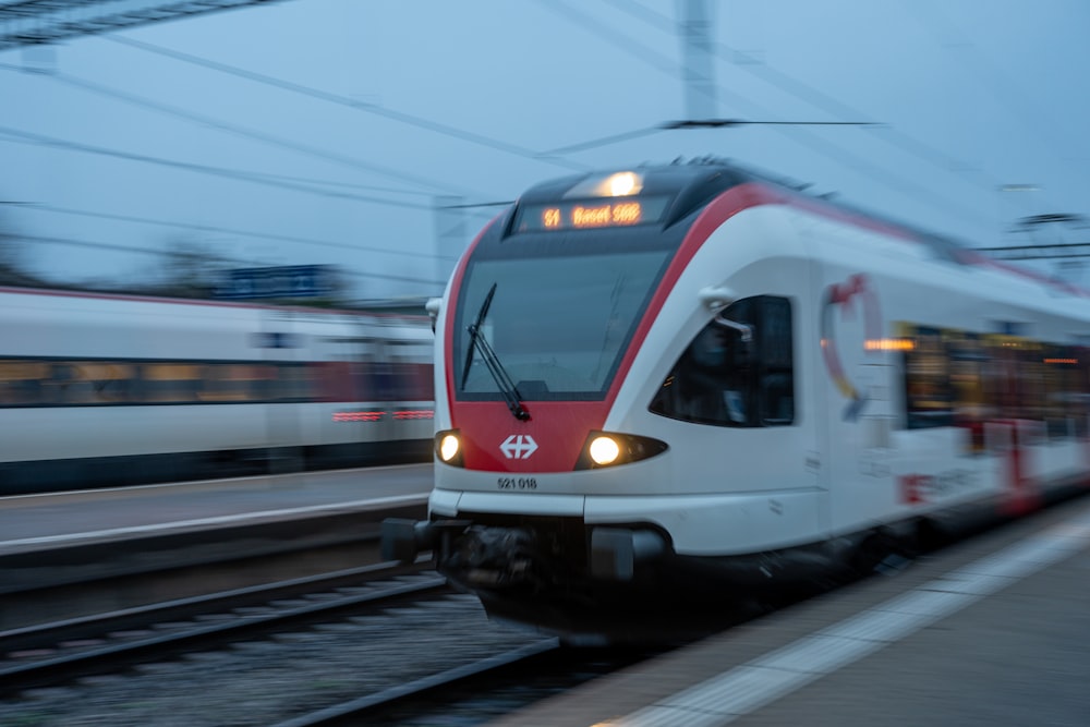 Ein rot-weißer Zug fährt die Gleise hinunter